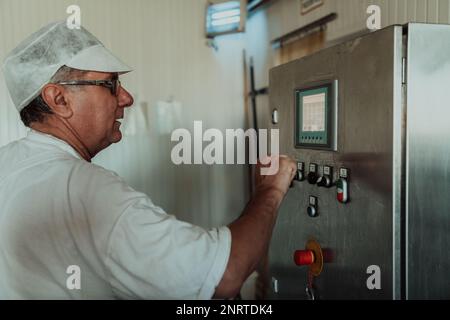 Cheese maker working in the modern industry on machines that are using for the machining of fresh cheese Stock Photo