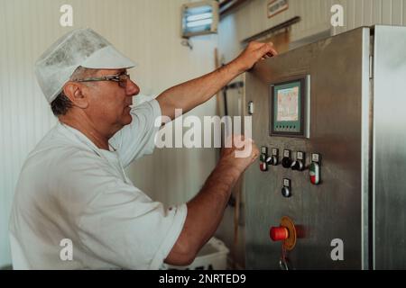 Cheese maker working in the modern industry on machines that are using for the machining of fresh cheese Stock Photo