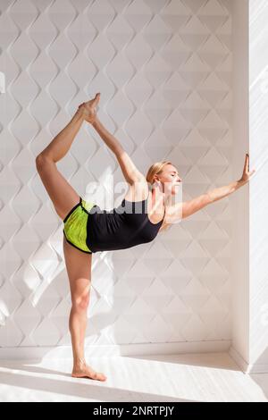 Young happy fitness model woman athlete  doing stretching workout near sunny solar bright wall. Healthy life bodybuilding lifestyle concept image, cop Stock Photo