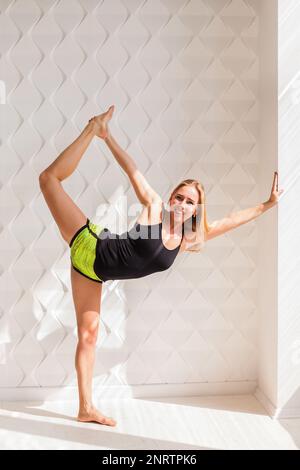 Young happy fitness model woman athlete  doing stretching workout near sunny solar bright wall. Healthy life bodybuilding lifestyle concept image, cop Stock Photo