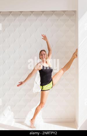 Young happy fitness model woman athlete  doing stretching workout near sunny solar bright wall. Healthy life bodybuilding lifestyle concept image, cop Stock Photo
