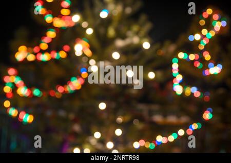Light blurred multicolored lights on a real Christmas tree outside in the snow. Bokeh. Stock Photo