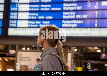 Young woman looking at the display board in a railway station (Model released) Stock Photo