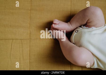 Close-up of babys legs lying in bed. Stock Photo