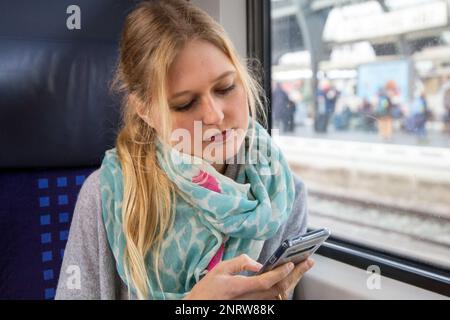 Young woman on the train looking at her smartphone (model released) Stock Photo