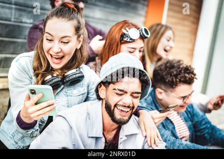 Happy trendy friends having fun with mobile phone at urban city streets - Young guys and girls spending time together sharing video on smartphone Stock Photo