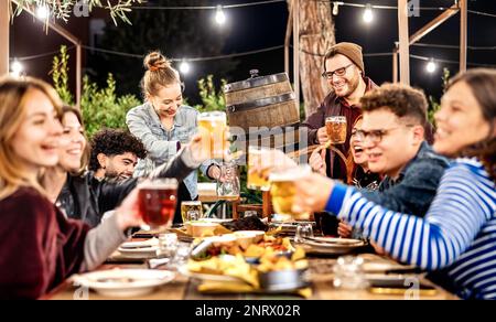 Young men and women having fun drinking out at beer garden patio - Social gathering and beverage life style concept on happy people enjoying weekend Stock Photo