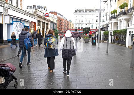 Rear back view of mother and teenage son boy 13 people visitors walking in street  London during half term school break February 2023 UK  KATHY DEWITT Stock Photo