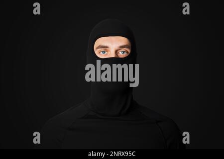 A man in a black mask. Thief, bandit. On a black background. Robbery. Stock Photo