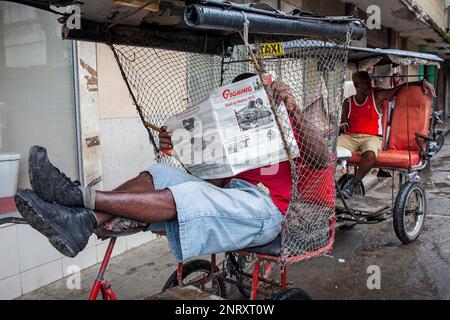 Man reading the Granma newspaper,Taxi pedicab waiting for clients, Street scene in San Rafael street at Galiano avenida, Centro Habana district, Haban Stock Photo