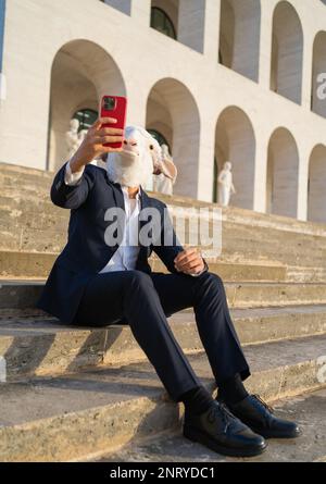vertical photo of business with sheep head sitting taking a selfie on lunch break Stock Photo