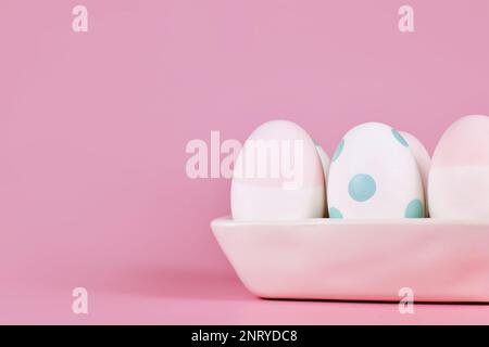 Pastel colored painted Easter eggs in egg box on pink background with copy space Stock Photo