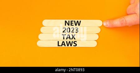 New 2023 tax laws symbol. Concept words New 2023 tax laws on wooden stick. Businessman hand. Beautiful orange table orange background. Business new 20 Stock Photo