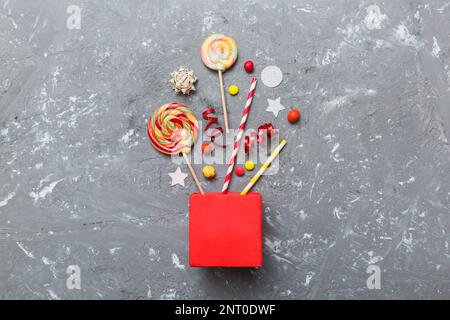 gift box in corner full of assorted traditional candies falling out on colored background with copy space. Happy Holidays sale concept. Stock Photo
