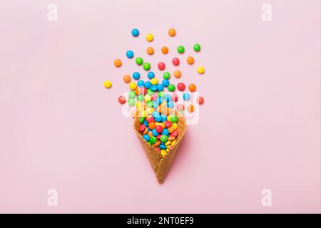 waffle cone full of assorted traditional candies falling out on colored background with copy space. Happy Holidays sale concept. Stock Photo