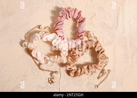 Silk scrunchies and necklace on pink background Stock Photo - Alamy