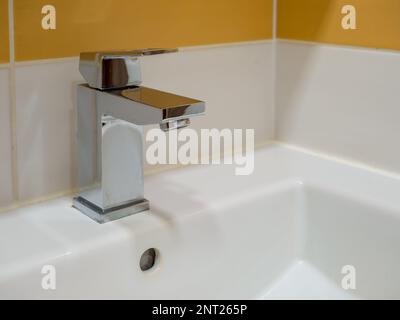 A white sink in a modern bathroom with a square faucet. Stock Photo