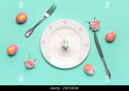 Table setting with Easter rabbit, eggs and flowers on mint background Stock Photo