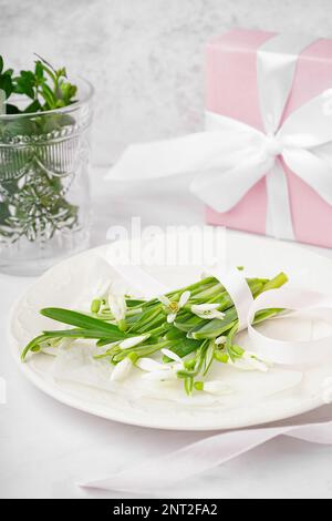 Plate with beautiful snowdrops and ribbon on white table Stock Photo