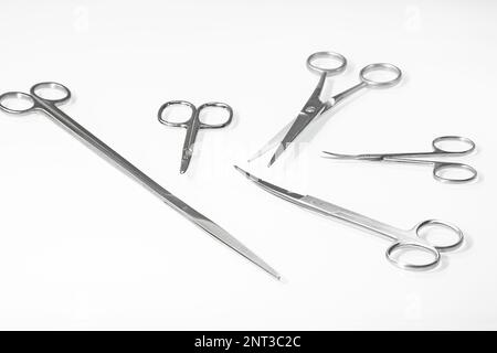 A set of various scissors for a hairdresser on a light background with a reflection in a white mirror table Stock Photo