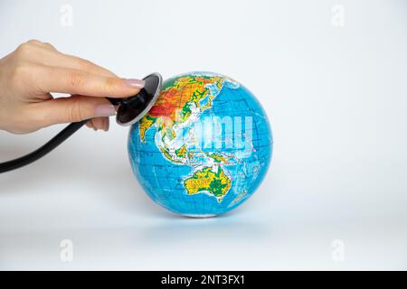 The globe in Ukrainian and the hand holds the stethoscope over the globe on a white background close -up Stock Photo