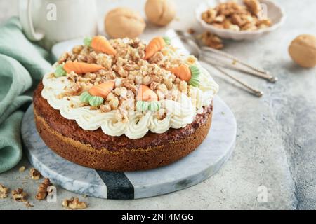 Easter Carrot cake with cream cheese frosting. Delicious carrot cake with walnut and cream cheese frosting on gray concrete background table for festi Stock Photo