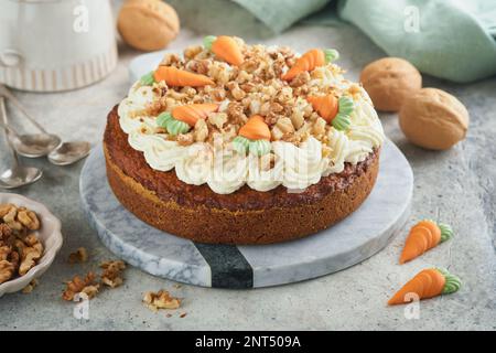 Easter Carrot cake with cream cheese frosting. Delicious carrot cake with walnut and cream cheese frosting on gray concrete background table for festi Stock Photo