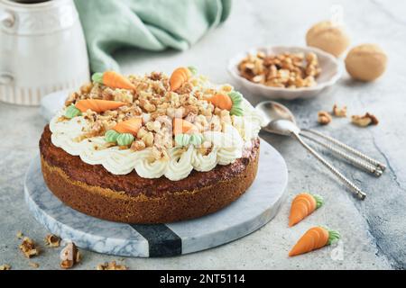 Easter Carrot cake with cream cheese frosting. Delicious carrot cake with walnut and cream cheese frosting on gray concrete background table for festi Stock Photo