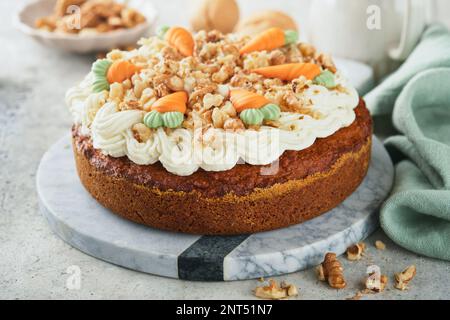 Easter Carrot cake with cream cheese frosting. Delicious carrot cake with walnut and cream cheese frosting on gray concrete background table for festi Stock Photo