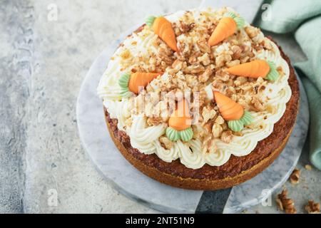 Easter Carrot cake with cream cheese frosting. Delicious carrot cake with walnut and cream cheese frosting on gray concrete background table for festi Stock Photo