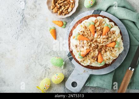 Easter Carrot cake with cream cheese frosting. Delicious carrot cake with walnut and cream cheese frosting on gray concrete background table for festi Stock Photo