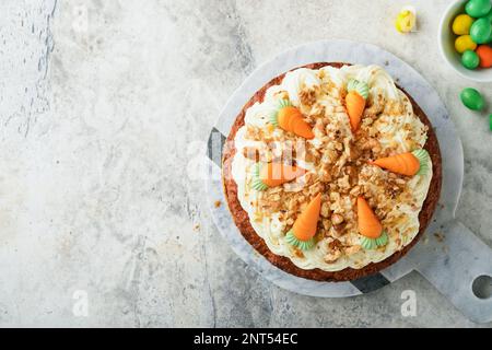Easter Carrot cake with cream cheese frosting. Delicious carrot cake with walnut and cream cheese frosting on gray concrete background table for festi Stock Photo
