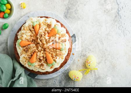 Easter Carrot cake with cream cheese frosting. Delicious carrot cake with walnut and cream cheese frosting on gray concrete background table for festi Stock Photo