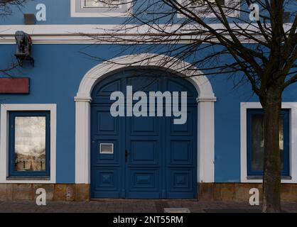 building with old blue gate and white framed window in old town.. Stock Photo