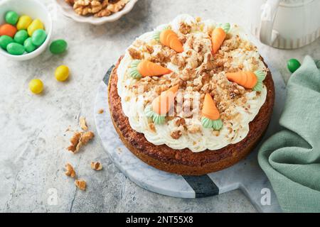 Easter Carrot cake with cream cheese frosting. Delicious carrot cake with walnut and cream cheese frosting on gray concrete background table for festi Stock Photo