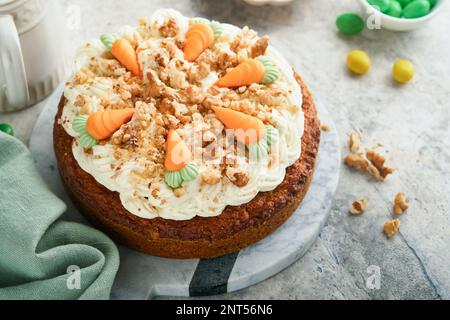 Easter Carrot cake with cream cheese frosting. Delicious carrot cake with walnut and cream cheese frosting on gray concrete background table for festi Stock Photo