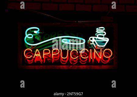 Neon light on a brick wall saying "Cappuccino". Stock Photo