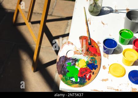 Close up of colorful paints, painting palette and brushes on table in garden Stock Photo