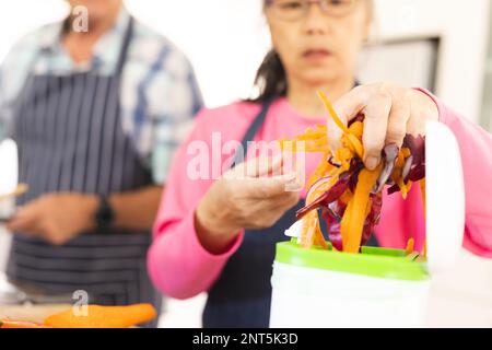 Happy senior diverse couple cleaning waste in kitchen Stock Photo