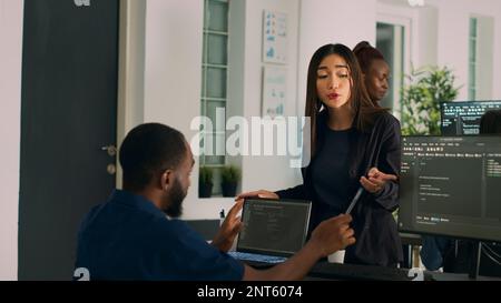 Diverse database developers doing highfive gesture with colleague programer, analyzing compiling code on computer. System engineers celebrating successful data server coding, artificial intelligence. Stock Photo