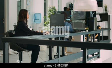 Asian woman programer focused on writing code in software development office, using big security data on terminal window. Database developer concentrating on creating algorithm for it agency. Stock Photo