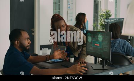 African american team of engineers working on server development with html script and terminal window. Computers being hacked and developers having no access in agency system network. Stock Photo