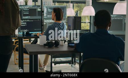 African american it engineer writing code on laptop and computer, analyzing html script on terminal window. Database admin developing algorithms for artificial intelligence cloud computing. Stock Photo