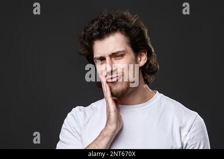 young man with toothache on dark gray background Stock Photo