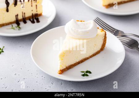 Slice of a traditional New York cheesecake with dollop whipped cream Stock Photo