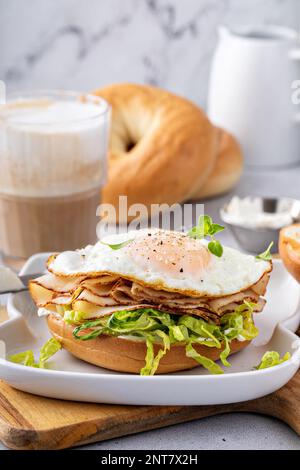 Bagel with cream cheese, shredded lettuce, sliced turkey and fried egg, breakfast sandwich idea Stock Photo