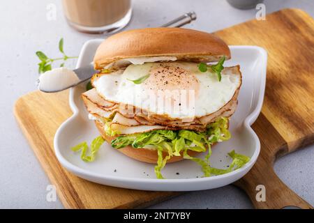 Bagel with cream cheese, shredded lettuce, sliced turkey and fried egg, breakfast sandwich idea Stock Photo