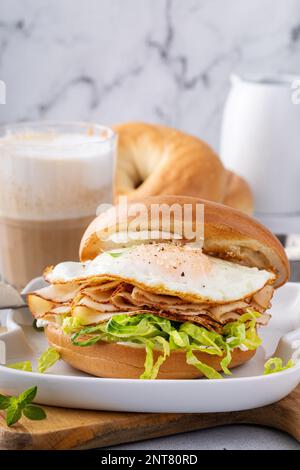 Bagel with cream cheese, shredded lettuce, sliced turkey and fried egg, breakfast sandwich idea Stock Photo