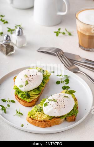 Sourdough toast with mashed avocado and poached eggs with herbs, healthy breakfast idea Stock Photo