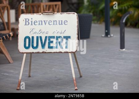 Metallic outdoor shop sign stating in french “Bienvenue, Entrez, c'est OUVERT”, meaning in english “Welcome, Enter, it's OPEN”. Stock Photo